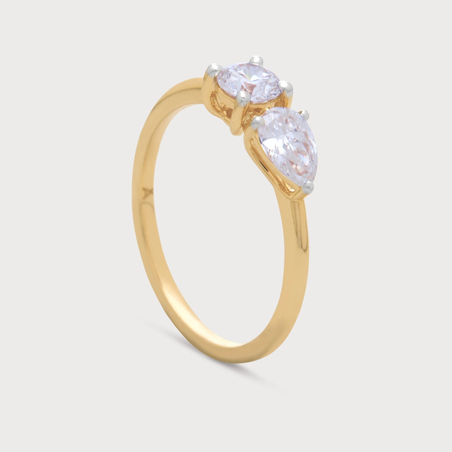 The Fleur Sol Ring, a golden diamond ring featuring a brilliant round cut diamond and an elegant pear-shaped diamond, suitable for engagement or special occasion jewelry.