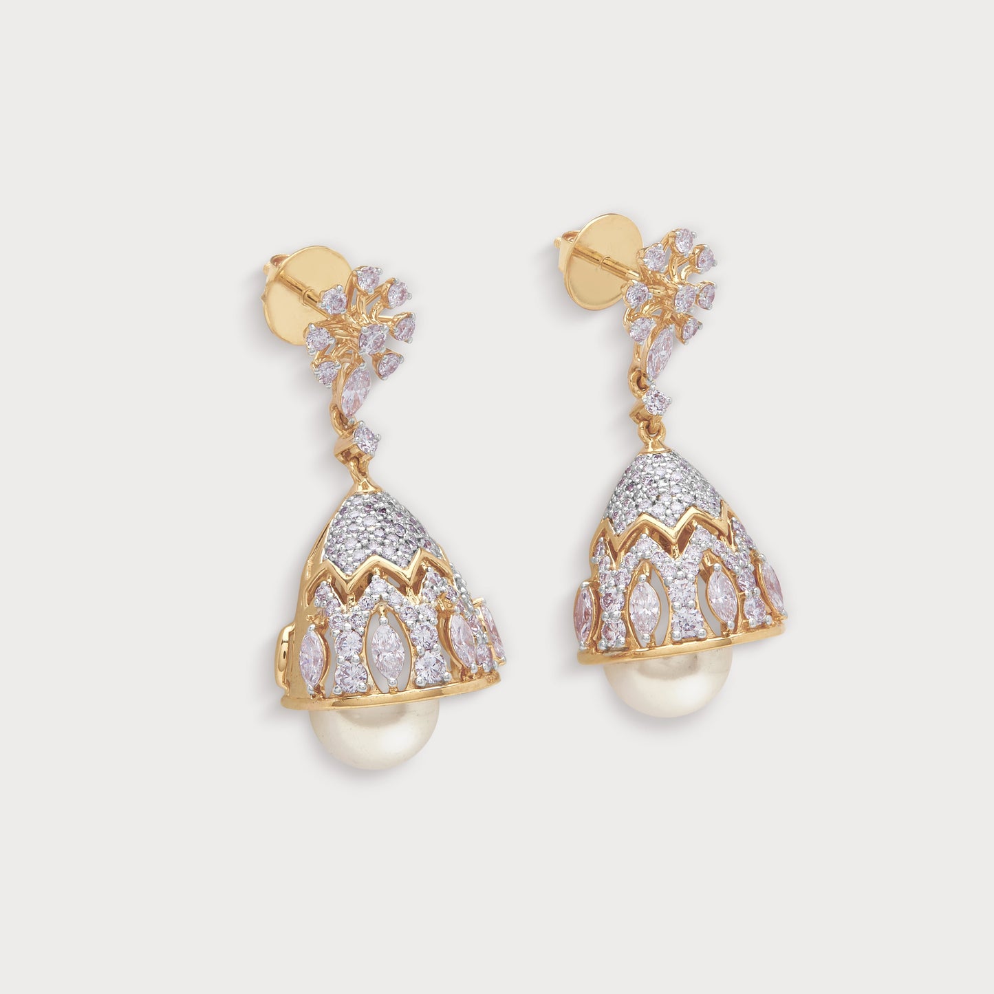 Flora Jhumkas: A pair of opulent gold diamond jhumka earrings featuring a floral stud, intricate bell-shaped drops set with sparkling white diamonds, and dangling pearl accents. High-quality diamond jewelry.