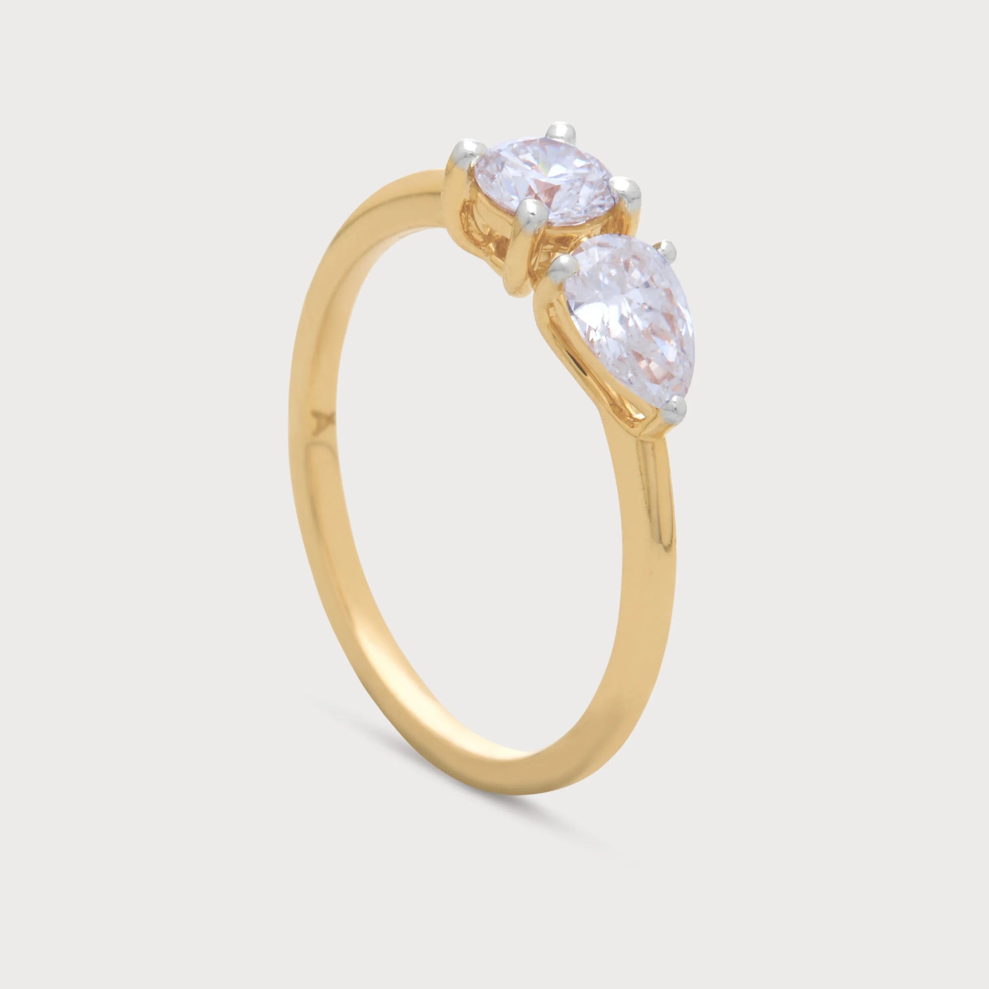 The Fleur Sol Ring, a golden diamond ring featuring a brilliant round cut diamond and an elegant pear-shaped diamond, suitable for engagement or special occasion jewelry.