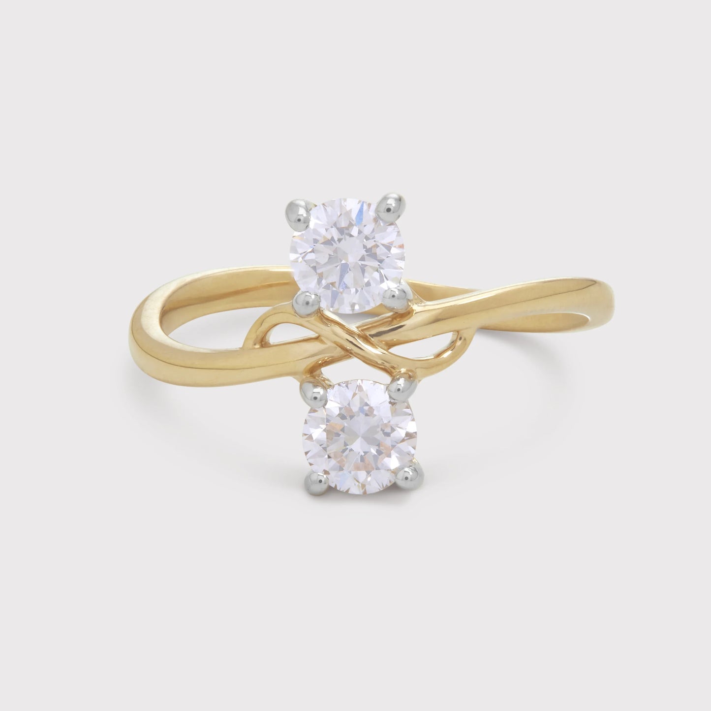 The Anedra Ring: A stunning two-stone bypass ring featuring two round brilliant diamonds set in a twisted yellow gold band. Perfect for engagement, anniversary, or a meaningful gift from a fine diamond jewelry store.