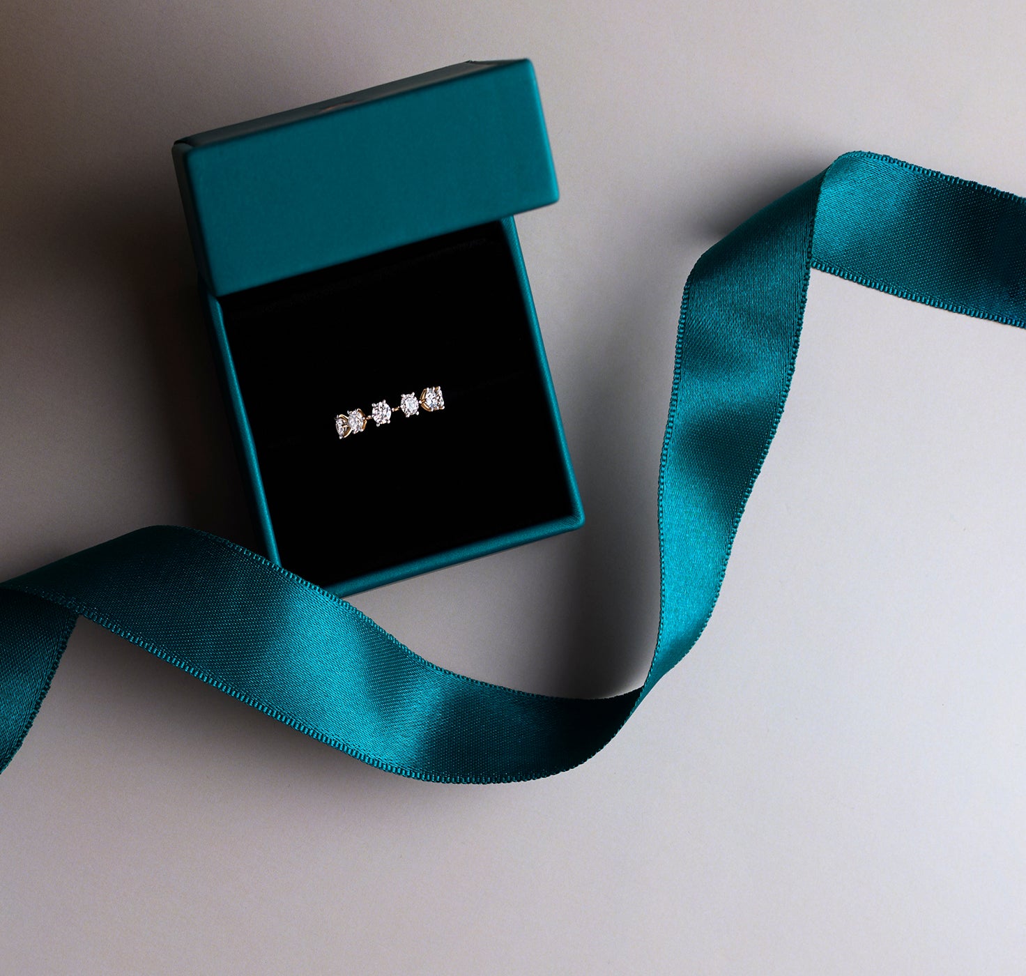 Elegant five-diamond gold ring in a premium teal jewelry gift box with a matching satin ribbon.