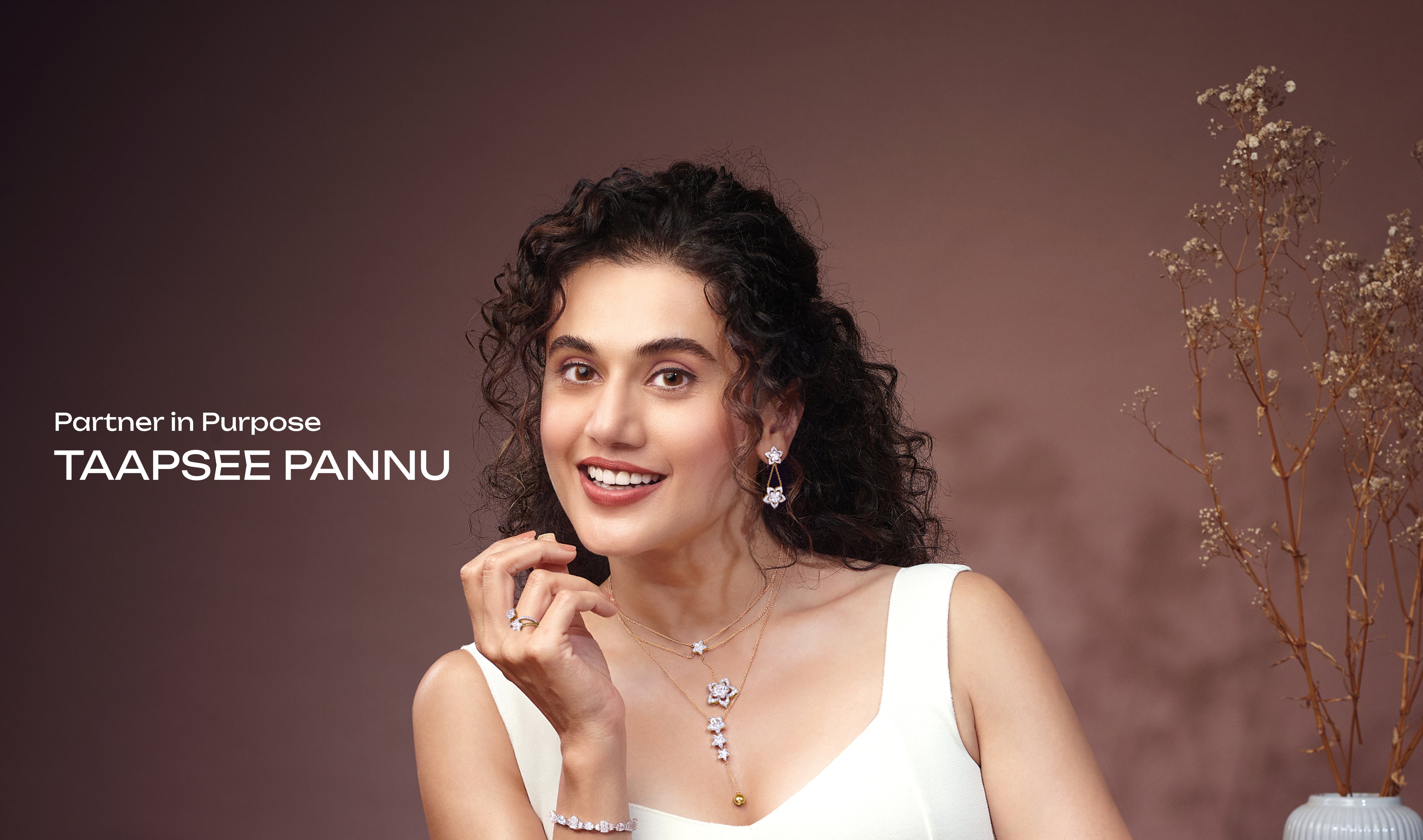 Indian actress Taapsee Pannu, 'Partner in Purpose', models a collection of elegant diamond jewelry including floral diamond earrings, a multi-layered diamond necklace with star motifs, a sparkling diamond ring, and a sophisticated diamond bracelet. This image promotes diamond jewelry for an e-commerce store.
