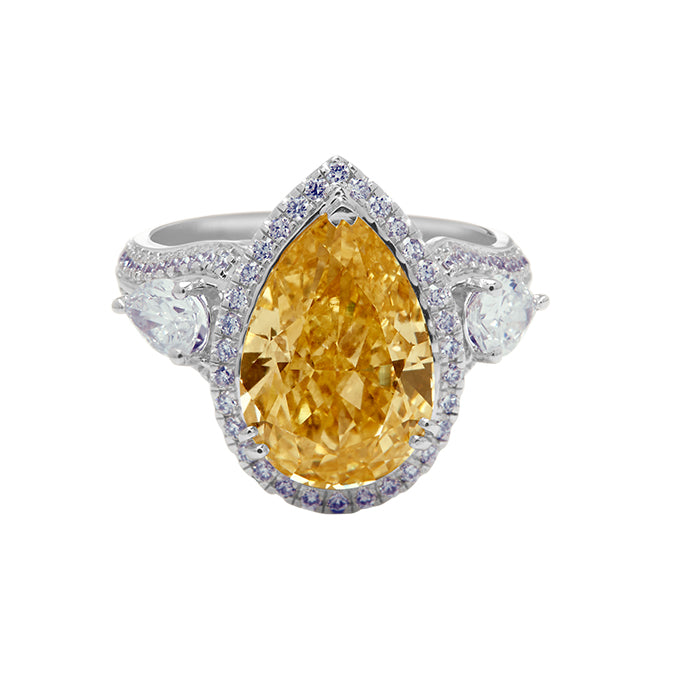 The Champagne Crowned Pear Ring, a luxurious diamond ring featuring a fancy champagne pear-shaped diamond centerpiece with a white diamond halo and two pear-cut diamond side stones, set in white gold. Ideal for engagement or special occasions.
