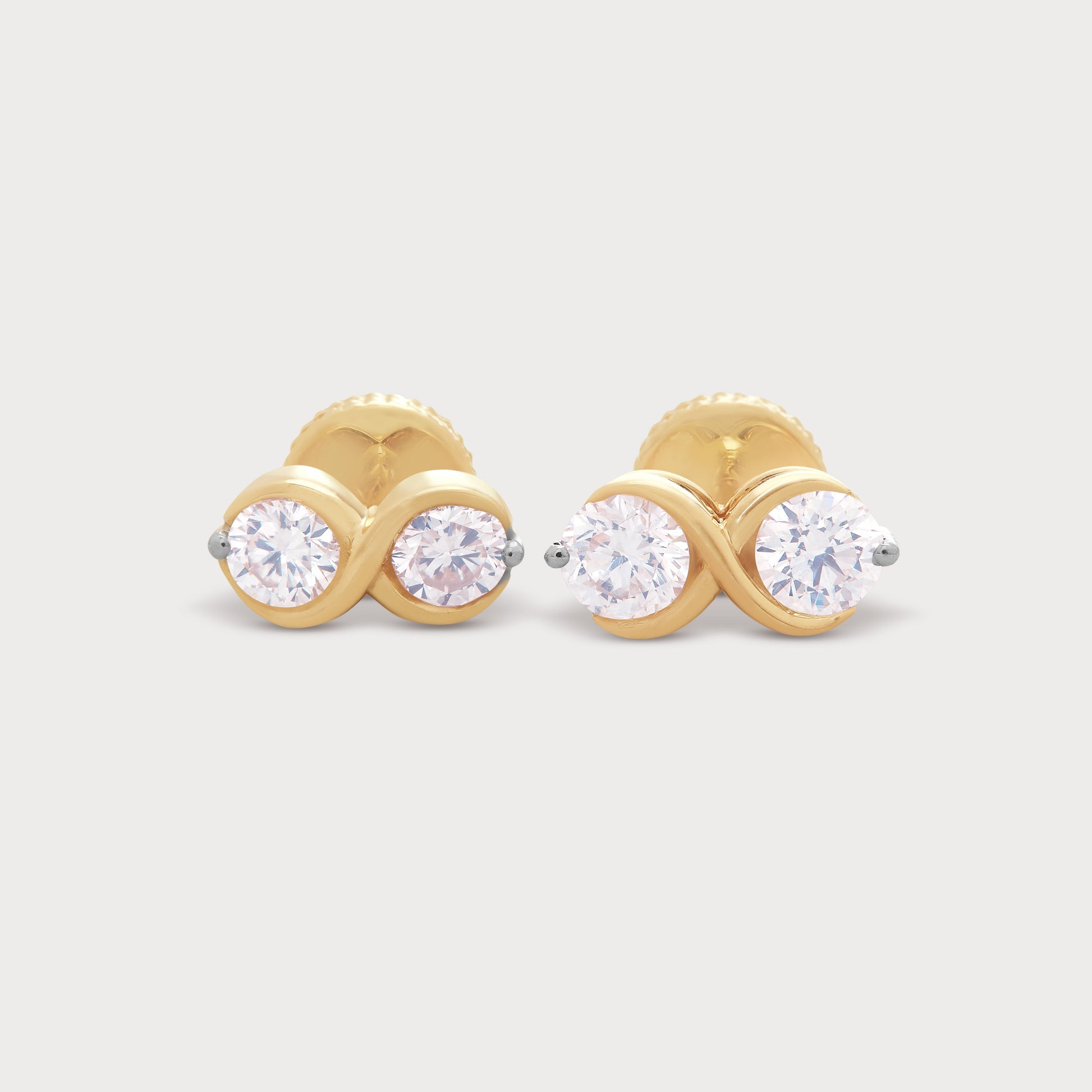 The Binolo Studs: A pair of exquisite yellow gold diamond stud earrings, each featuring two brilliant round diamonds in a modern, intertwined design.