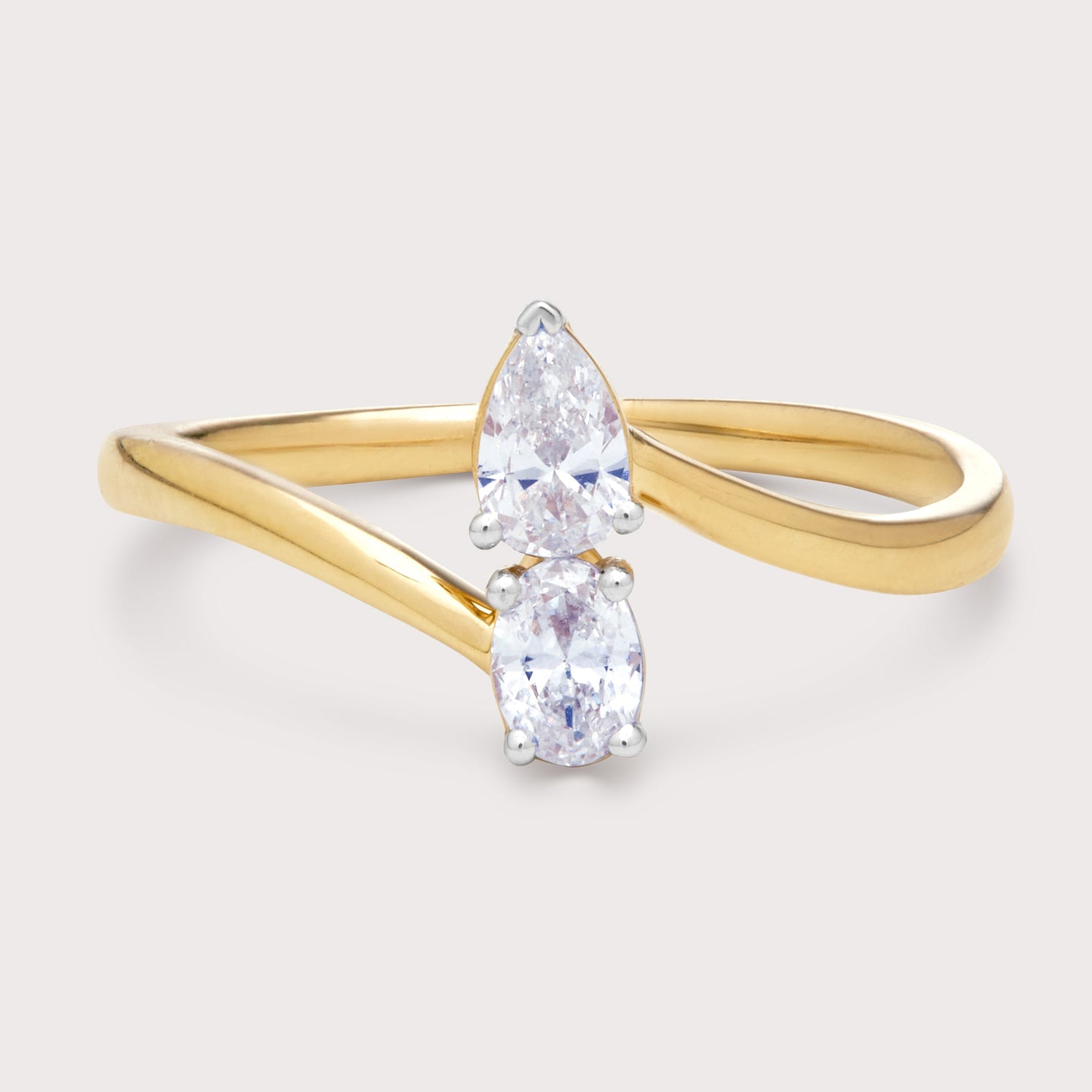 The Alari Ring: two-stone bypass diamond ring featuring a pear-shaped diamond and an oval-shaped diamond on a yellow gold band. Fine diamond jewelry for e-commerce.